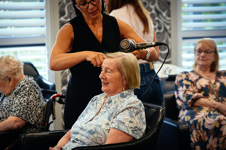 A resident having her hair styled in the on-site salon