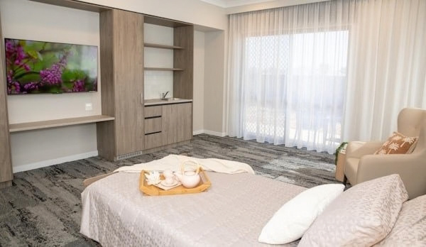 A bedroom with a wall-mounted smart TV and built-in storage
